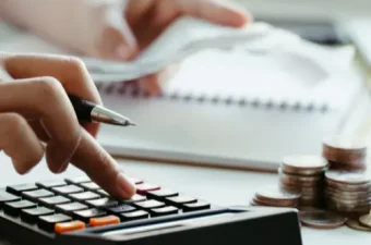 Symbolische Darstellung Mindestlohn 2027 mit Münzen, Taschenrechner und Gesetzbuch auf einem Schreibtisch im Betriebsratsbüro