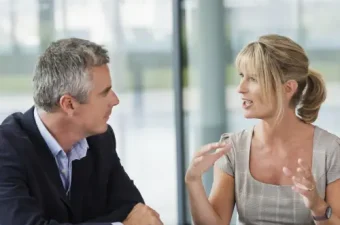 Zwei Personen sitzen sich bei einem Mitarbeitergespräch gegenüber, in der Mitte liegt ein Dokument zur fairen Leistungsbeurteilung, das durch den Betriebsrat geregelt wurde.