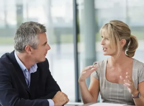 Zwei Personen sitzen sich bei einem Mitarbeitergespräch gegenüber, in der Mitte liegt ein Dokument zur fairen Leistungsbeurteilung, das durch den Betriebsrat geregelt wurde.