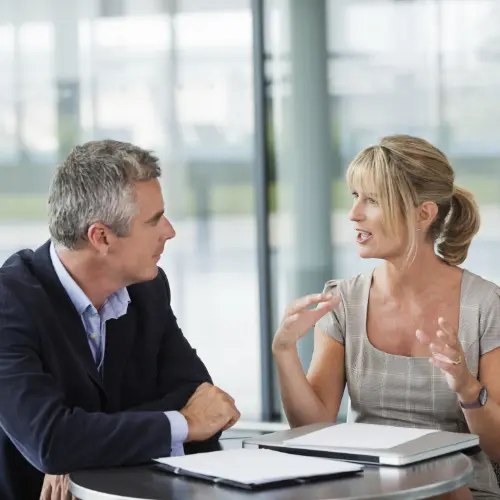 Zwei Personen sitzen sich bei einem Mitarbeitergespräch gegenüber, in der Mitte liegt ein Dokument zur fairen Leistungsbeurteilung, das durch den Betriebsrat geregelt wurde.