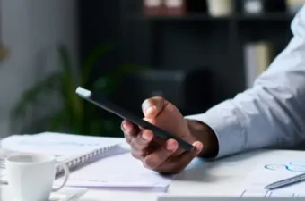 Mitarbeiter hält Smartphone in der Hand und postet auf LinkedIn – im Hintergrund das Büro, symbolisch für die Notwendigkeit einer Betriebsvereinbarung Social Media im Unternehmen