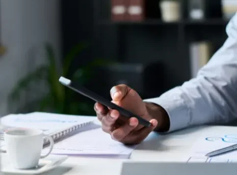 Mitarbeiter hält Smartphone in der Hand und postet auf LinkedIn – im Hintergrund das Büro, symbolisch für die Notwendigkeit einer Betriebsvereinbarung Social Media im Unternehmen