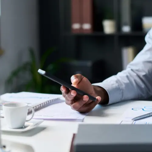 Mitarbeiter hält Smartphone in der Hand und postet auf LinkedIn – im Hintergrund das Büro, symbolisch für die Notwendigkeit einer Betriebsvereinbarung Social Media im Unternehmen