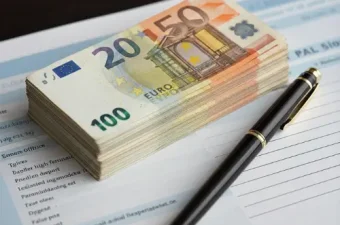 Ein Stapel Euro-Geldscheine liegt auf einem Gehaltszettel neben einem Stift, symbolisch für die Lohngestaltung und dauerhafte Gehaltserhöhungen im Betrieb.