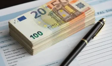 Ein Stapel Euro-Geldscheine liegt auf einem Gehaltszettel neben einem Stift, symbolisch für die Lohngestaltung und dauerhafte Gehaltserhöhungen im Betrieb.