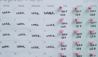 Ein Kalender auf einem modernen Schreibtisch, bei dem die Tage Montag bis Donnerstag farbig markiert sind, passend zum Thema 4-Tage-Woche im Praxistest.