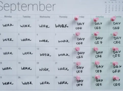 Ein Kalender auf einem modernen Schreibtisch, bei dem die Tage Montag bis Donnerstag farbig markiert sind, passend zum Thema 4-Tage-Woche im Praxistest.